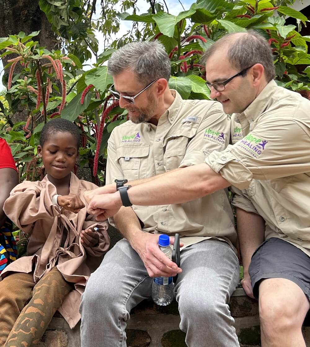 Steve Jones and his colleague giving a fist bump to a child receiving medical care through Hope and Healing International.