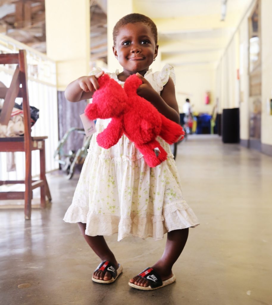 Happy female child holding a red teddy