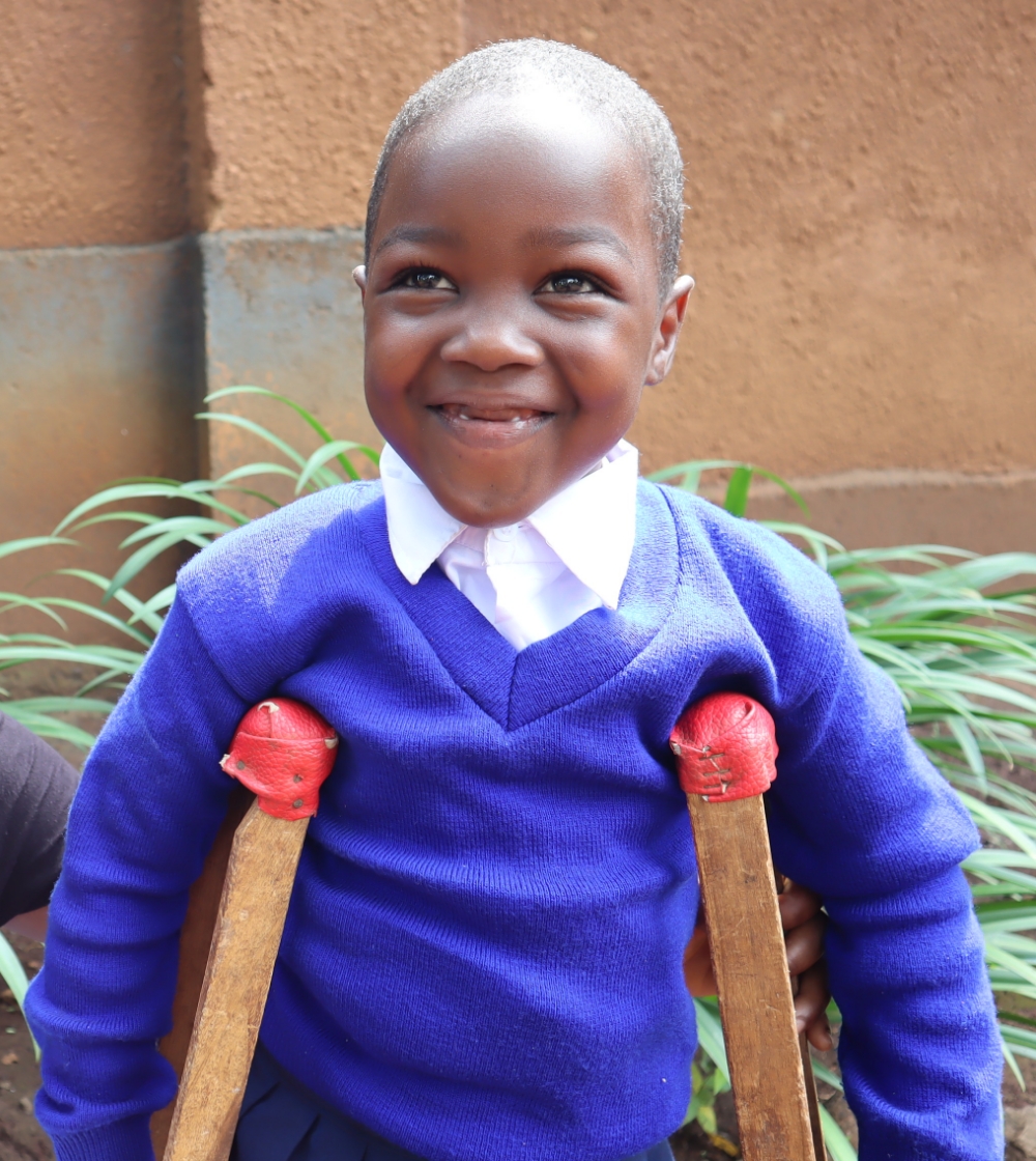 A young girl named Jenipher, smiling with her crutches as she goes off to school on her first day.