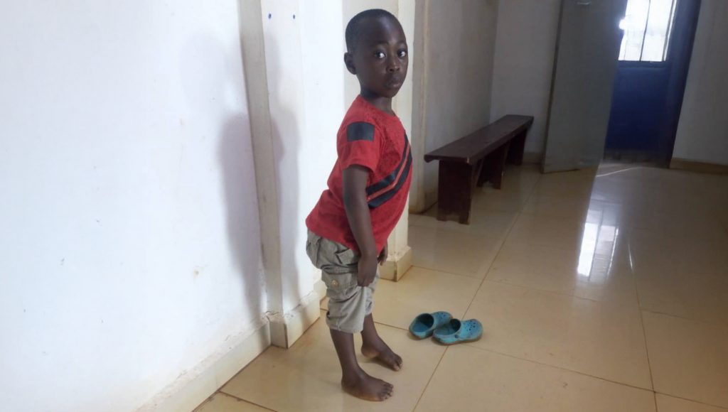 Serious boy in hallway standing on the side of his left foot.