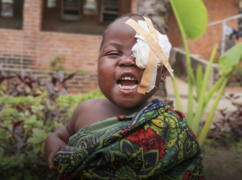 A smiling young girl wearing an eye patch.