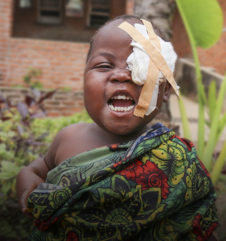 A smiling young girl wearing an eye patch.