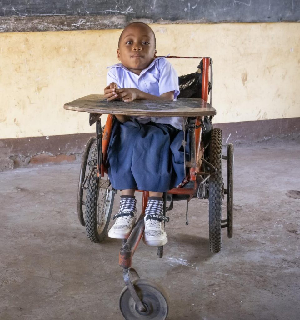 A girl sitting in a worn out wheelchair.