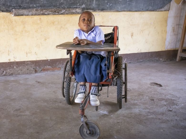 A girl sitting in a worn out wheelchair.