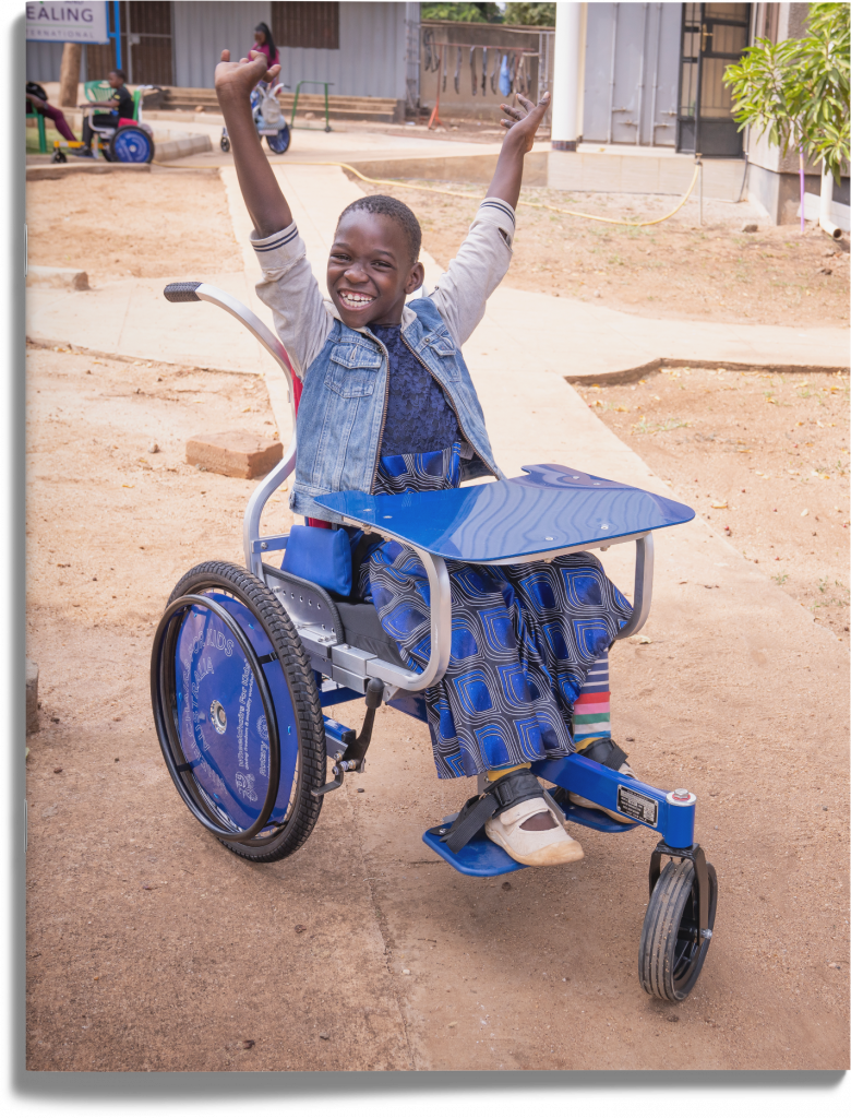 Epifania smiling with her arms raised in her wheelchair.