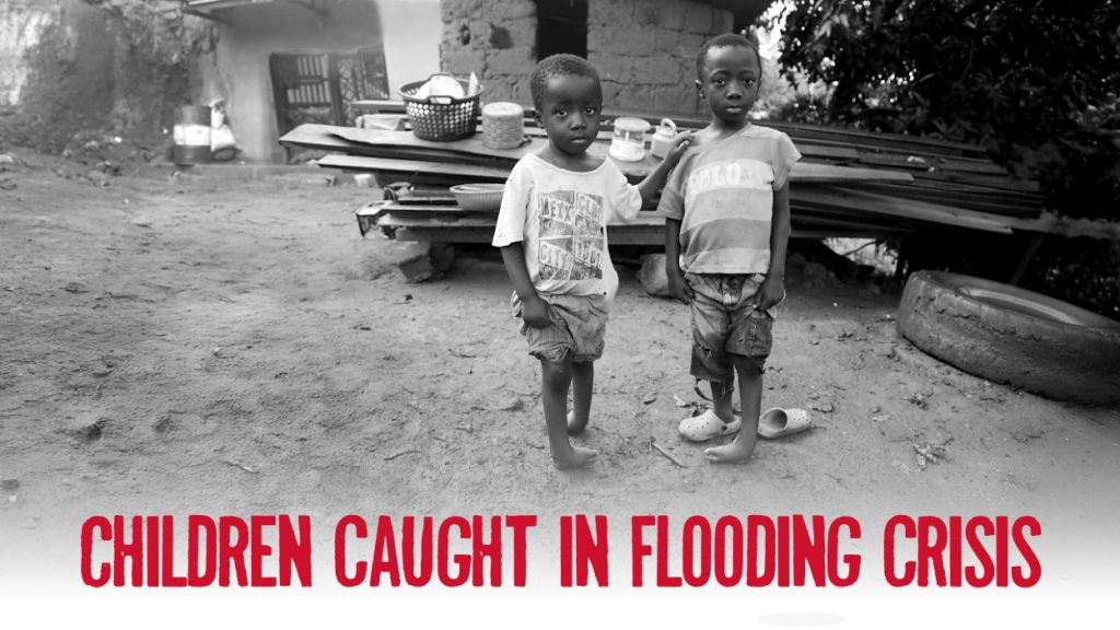 Two children standing on clubfeet in mud outside.